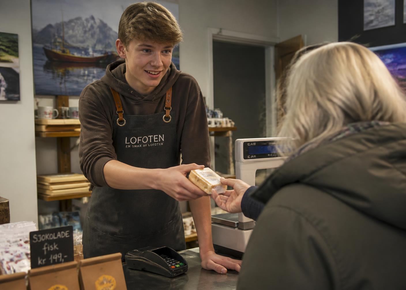 Elev i praksis betjener en kunde bak disken i en lokal butikk